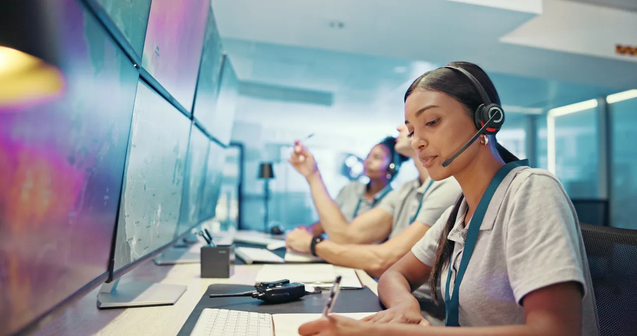 Dispatcher wearing a headset coordinating a response at a multi-screen workstation