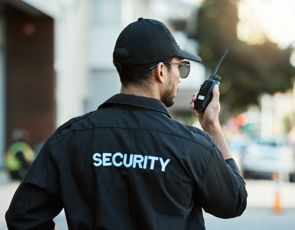 Security professional using a handheld radio outdoors